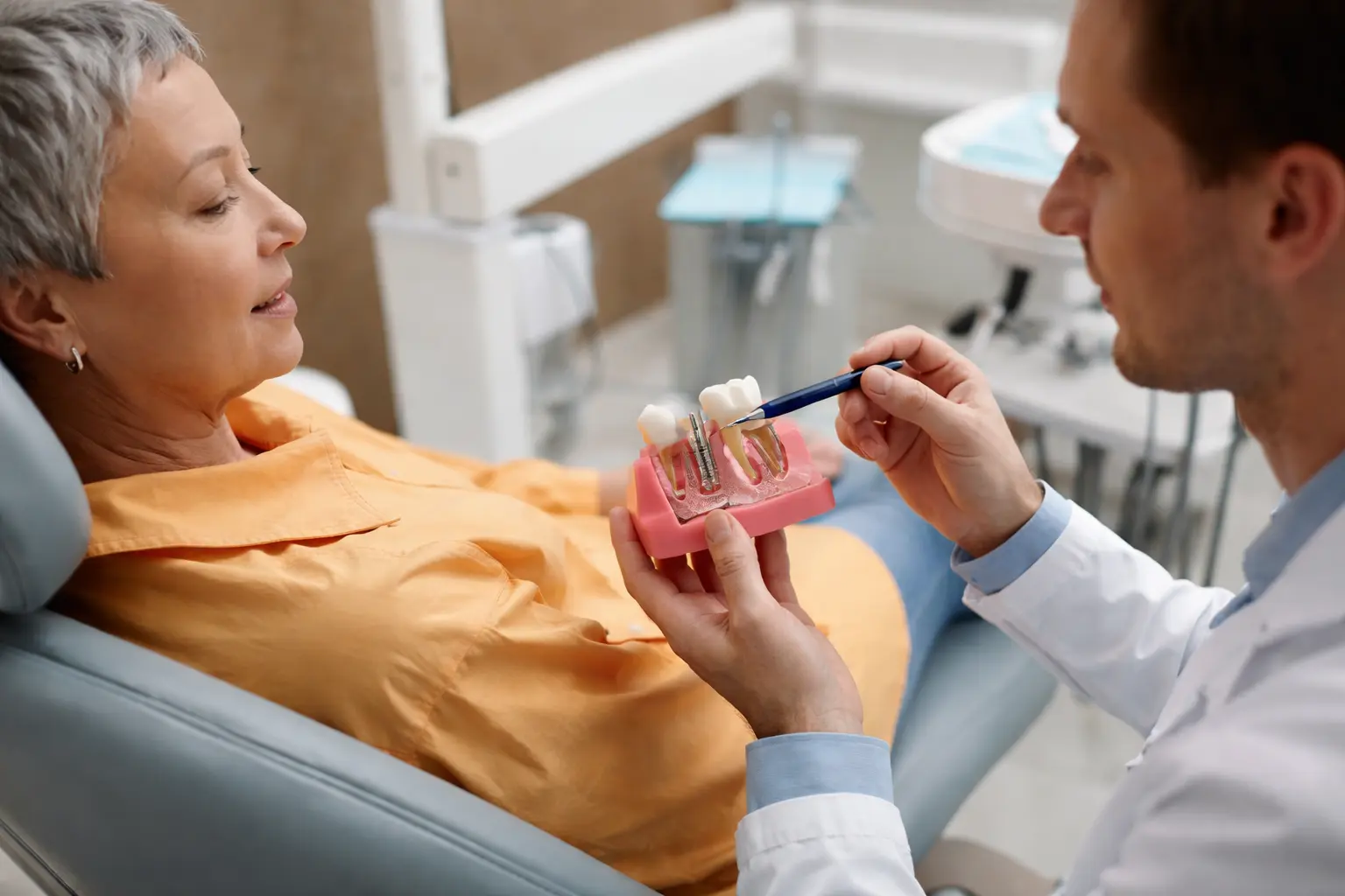 Dentista explicando um tratamento para paciente em ambiente claro, moderno e calmo